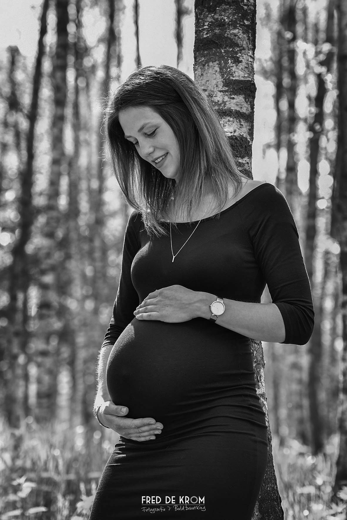 Zwart-wit foto van zwangere dame voor berkenbos.