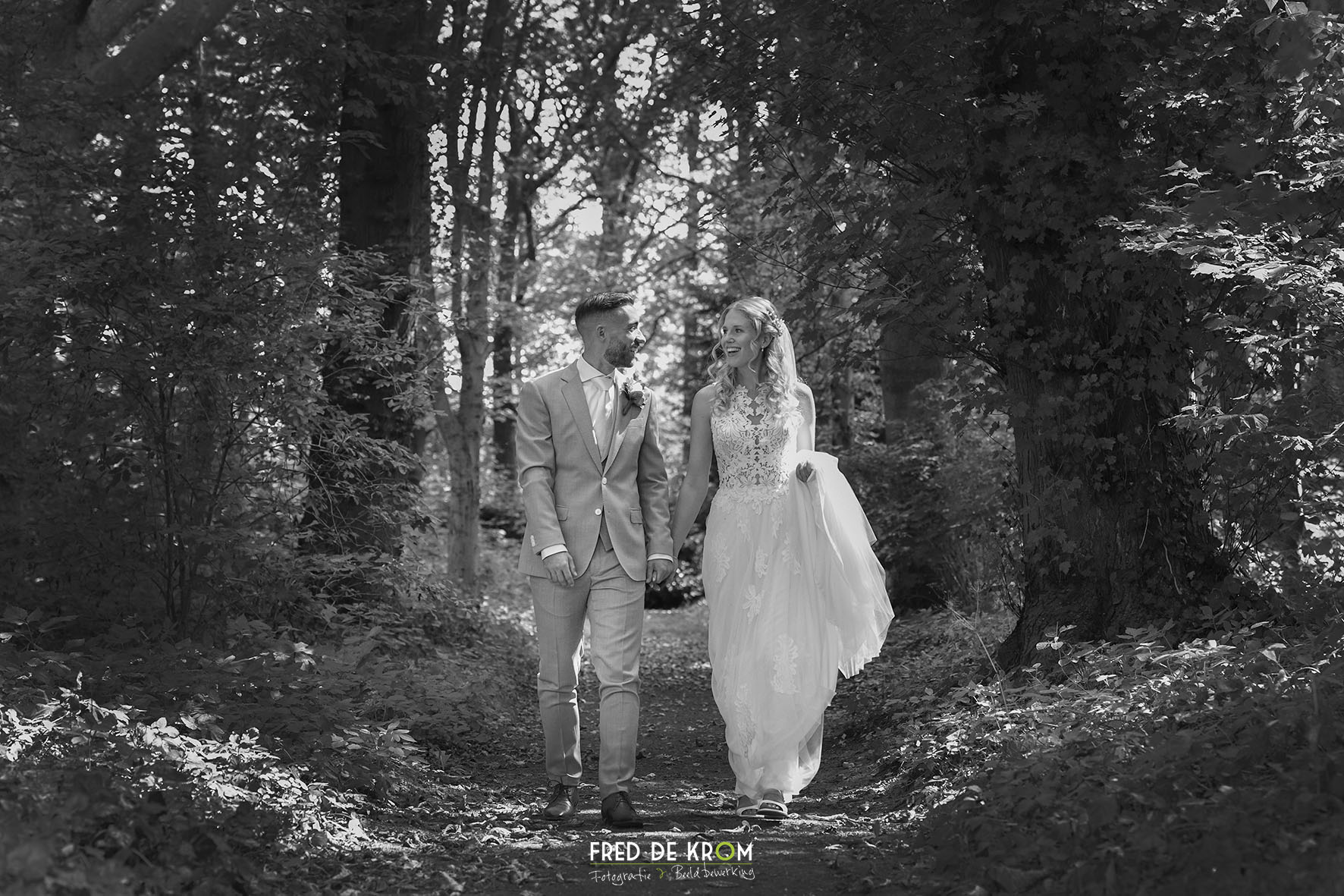 Bruidspaar wandelend op bospad bij kasteel Heeze. Zwart-wit foto.